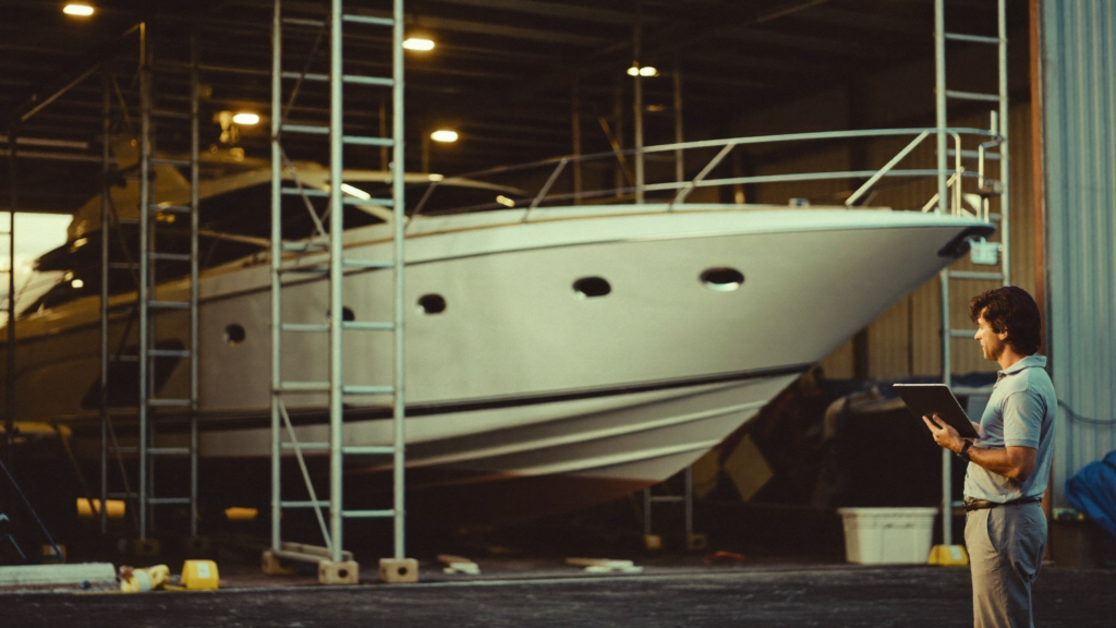 Superyacht in a covered refit shed with a project manager reviewing the work