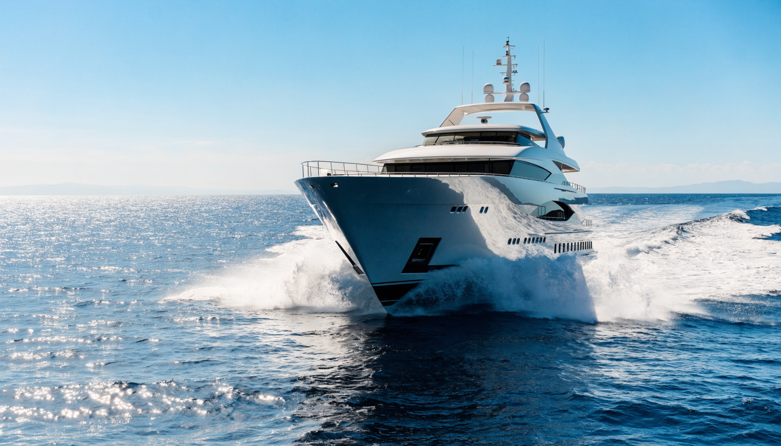 A large white motor superyacht cruising at speed on open blue ocean