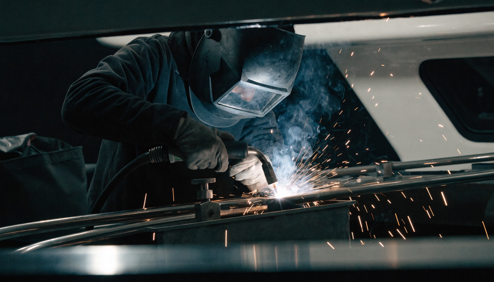 A marine welder fabricating stainless steel aboard a yacht with bright sparks