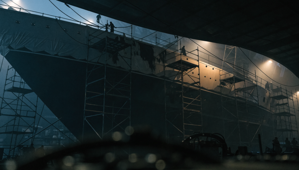 A superyacht under restoration inside a refit shed surrounded by scaffolding