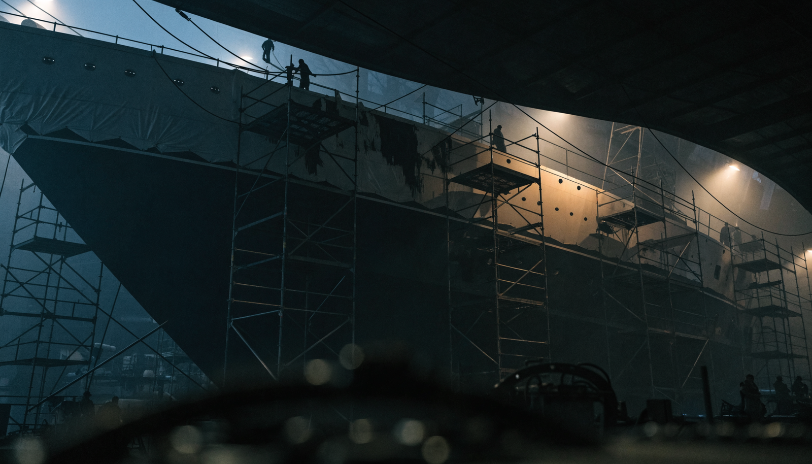 A superyacht under restoration inside a refit shed surrounded by scaffolding