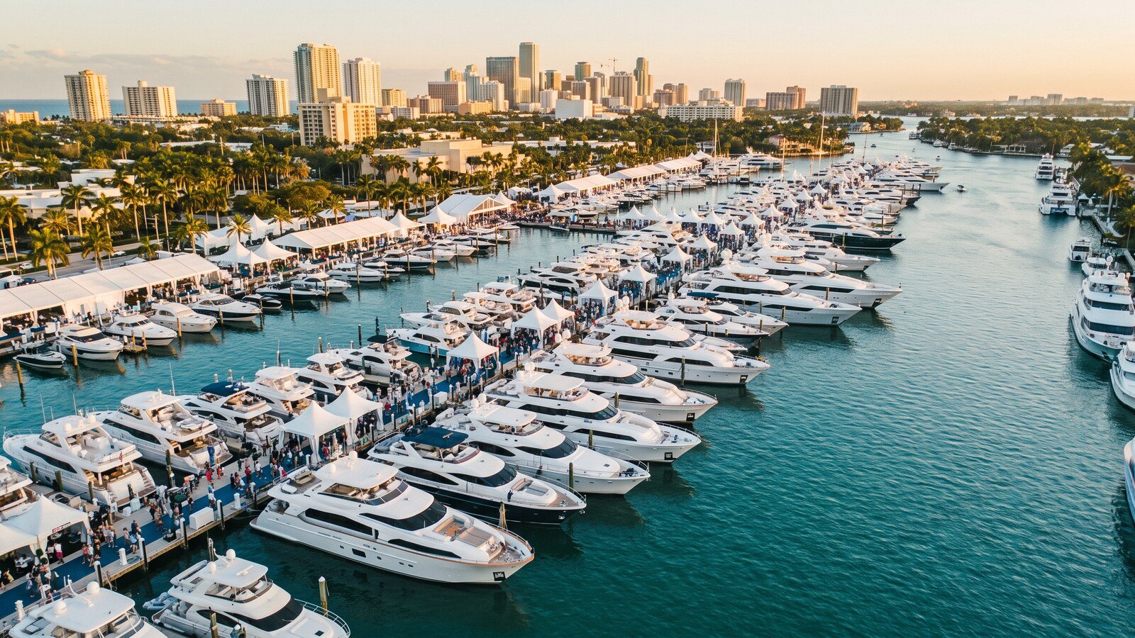 Illustration of an aerial view of boat show docks lined with motor yachts along a waterway at golden hour